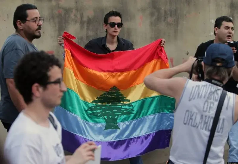 LGBT rights demonstrator holding a rainbow flag with the Lebanese cedar in 2018